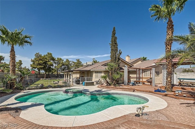 view of pool with a pool with connected hot tub, fence, and a patio