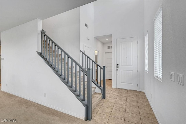 foyer with stairway, tile patterned floors, visible vents, and baseboards