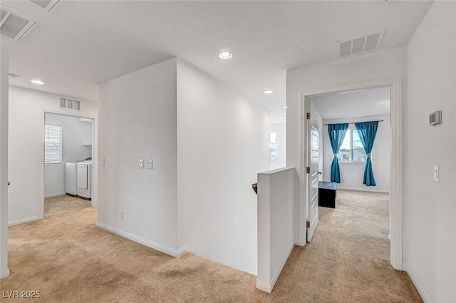 corridor featuring an upstairs landing, visible vents, carpet flooring, and washing machine and clothes dryer