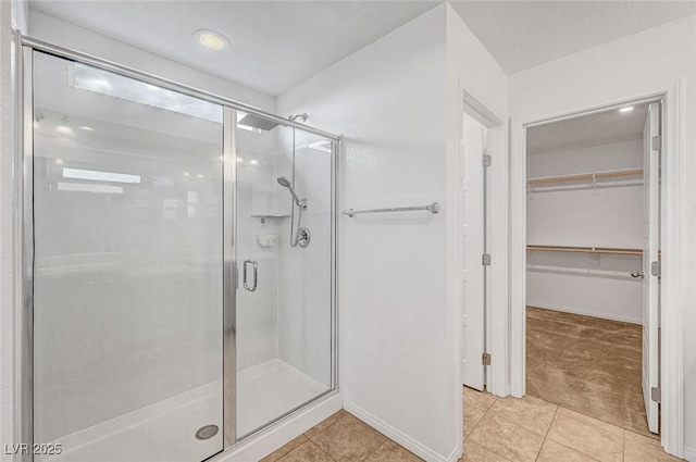 full bathroom featuring a stall shower, a walk in closet, and tile patterned floors