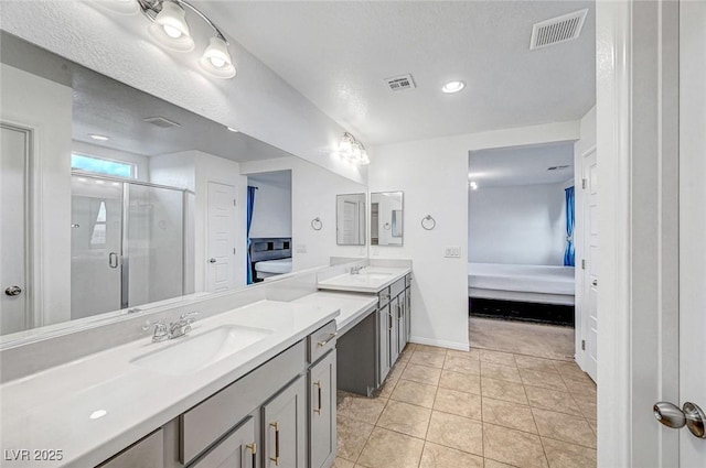 full bath with a sink, a stall shower, visible vents, and connected bathroom