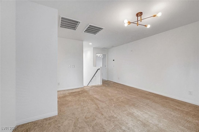 empty room featuring a chandelier, light carpet, visible vents, and baseboards