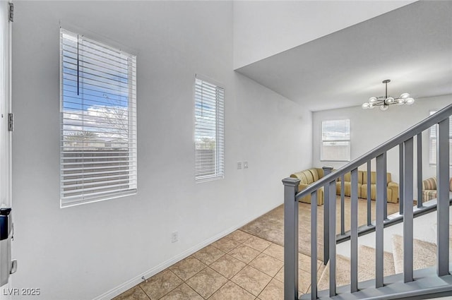 interior space featuring a notable chandelier, plenty of natural light, baseboards, and tile patterned floors