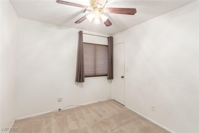 carpeted spare room featuring baseboards, a ceiling fan, and a textured ceiling