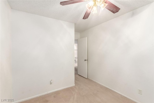 spare room featuring light carpet, a ceiling fan, a textured ceiling, and baseboards