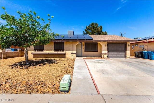 ranch-style home featuring concrete driveway, fence, a garage, roof mounted solar panels, and stucco siding