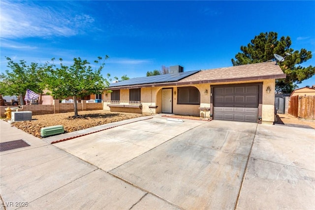 ranch-style home with roof mounted solar panels, fence, stucco siding, an attached garage, and covered porch