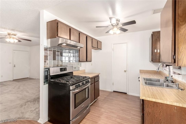 kitchen featuring stainless steel range with gas cooktop, a ceiling fan, under cabinet range hood, and a sink