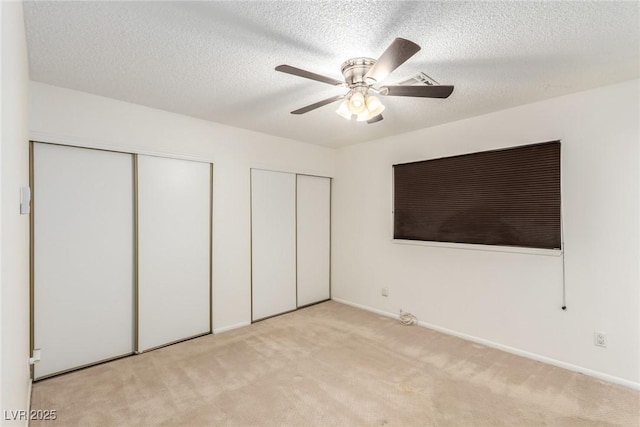 unfurnished bedroom with a ceiling fan, a textured ceiling, multiple closets, baseboards, and carpet flooring