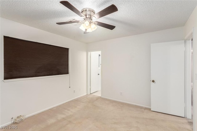 unfurnished room with a textured ceiling, a ceiling fan, baseboards, and light carpet