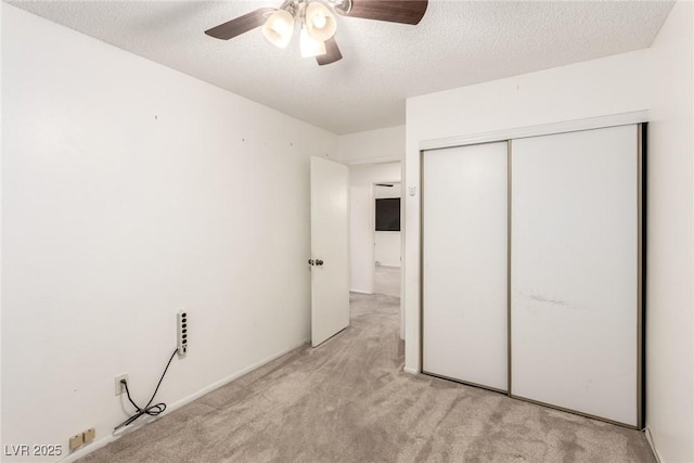unfurnished bedroom with a textured ceiling, ceiling fan, a closet, and light carpet
