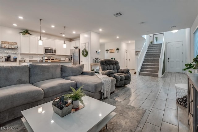 living area featuring recessed lighting, visible vents, and stairs