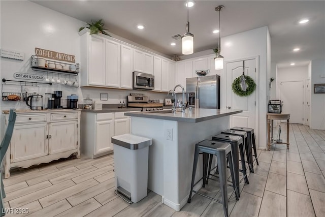 kitchen with appliances with stainless steel finishes, white cabinetry, a sink, and a breakfast bar area