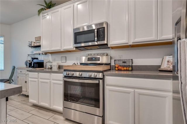 kitchen with dark countertops, appliances with stainless steel finishes, and white cabinets