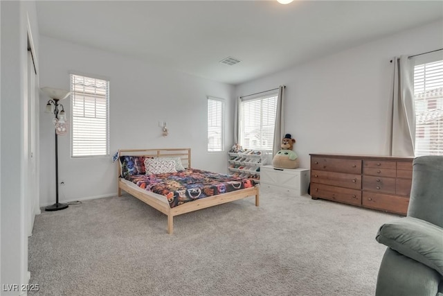 bedroom with carpet floors, visible vents, and multiple windows