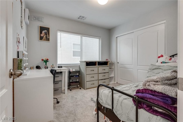 carpeted bedroom with a closet, a wall mounted air conditioner, and visible vents