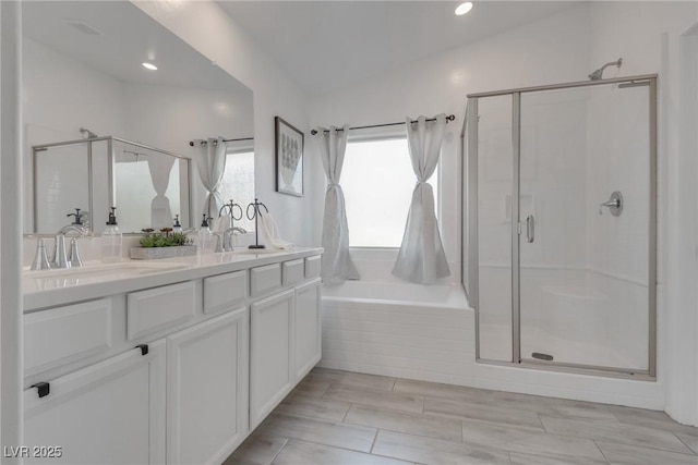 bathroom with double vanity, a stall shower, a garden tub, and a sink