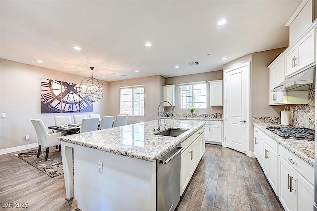 kitchen with wood finished floors, a sink, visible vents, appliances with stainless steel finishes, and a center island with sink