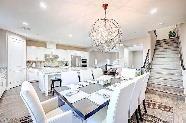 dining room with recessed lighting, visible vents, an inviting chandelier, light wood-style floors, and stairs