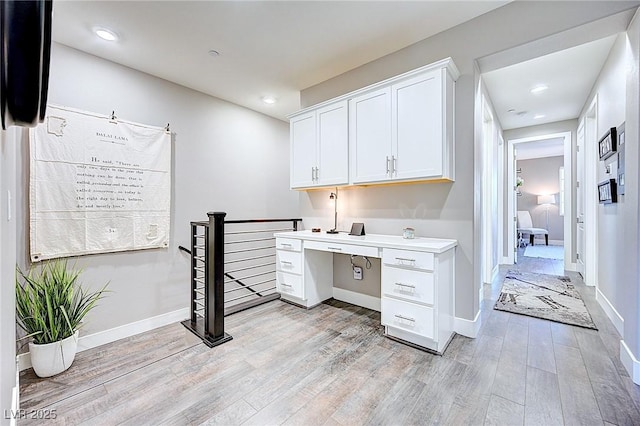 office with baseboards, built in study area, and light wood-style floors