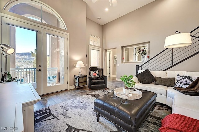 living area featuring baseboards, stairway, wood finished floors, a high ceiling, and french doors