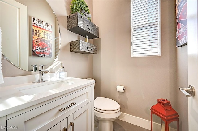 bathroom with vanity, toilet, and baseboards