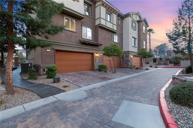 exterior space featuring central AC, decorative driveway, and an attached garage