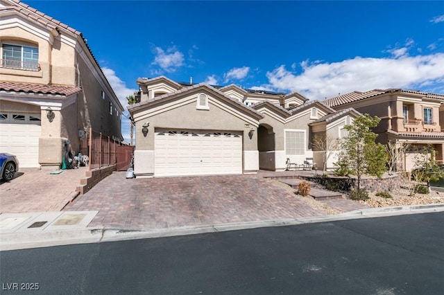 mediterranean / spanish home with stucco siding, decorative driveway, an attached garage, and a tile roof