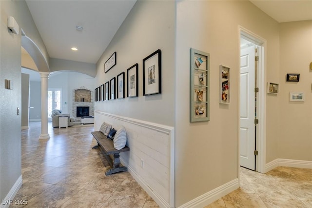 hall with arched walkways, recessed lighting, baseboards, and decorative columns