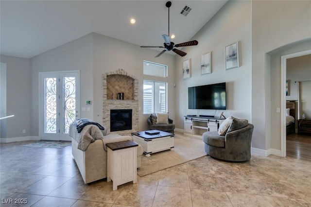 living room featuring light tile patterned floors, baseboards, visible vents, high vaulted ceiling, and a stone fireplace