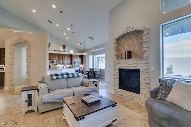 living room featuring visible vents, high vaulted ceiling, and a fireplace