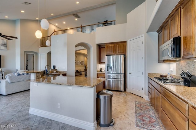 kitchen with arched walkways, a sink, ceiling fan, appliances with stainless steel finishes, and open floor plan