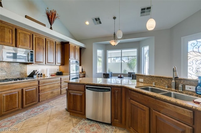 kitchen with light stone counters, visible vents, a sink, appliances with stainless steel finishes, and decorative light fixtures