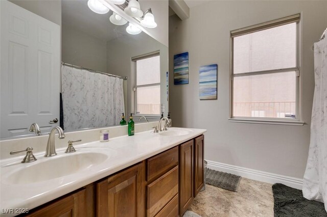 full bath with double vanity, baseboards, a wealth of natural light, and a sink