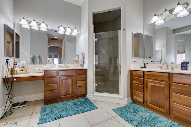 full bathroom with tile patterned floors, two vanities, a stall shower, and a sink