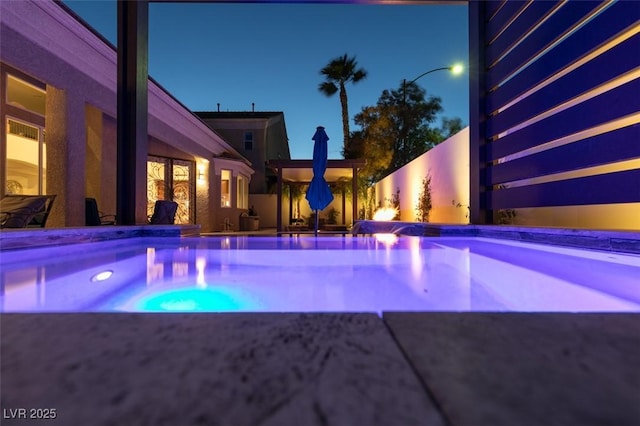 pool at twilight with a patio area, an outdoor pool, and a hot tub