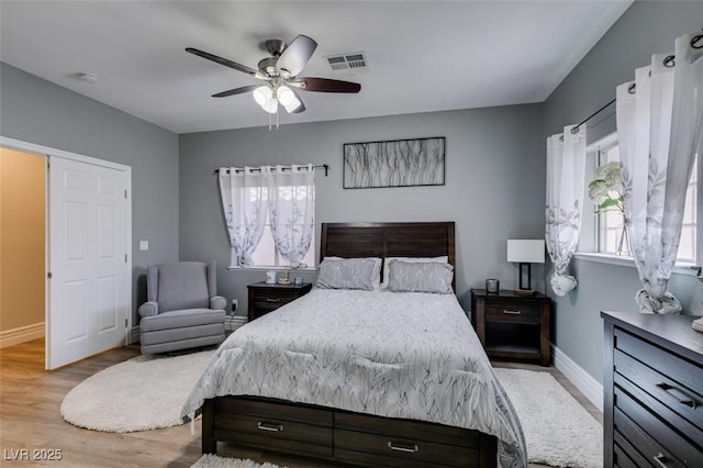 bedroom featuring visible vents, light wood-style floors, baseboards, and ceiling fan