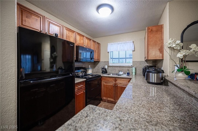 kitchen featuring black appliances, a textured ceiling, a sink, and a textured wall