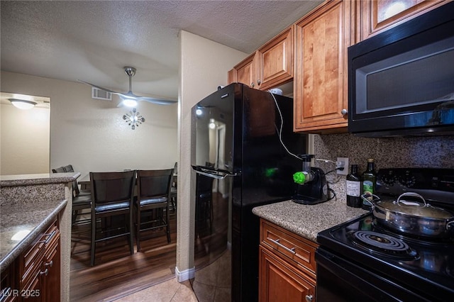 kitchen featuring visible vents, decorative backsplash, a ceiling fan, black appliances, and light tile patterned flooring