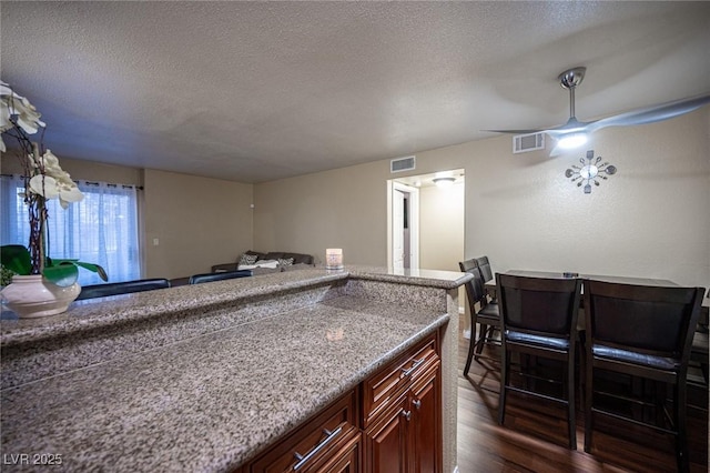 kitchen featuring dark wood-type flooring, visible vents, and a textured ceiling