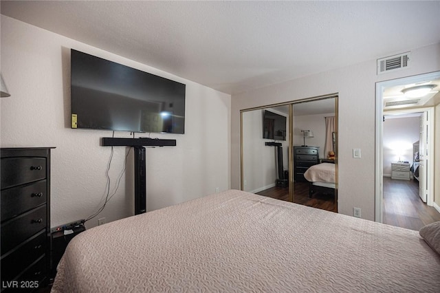 bedroom with dark wood-style floors, a closet, and visible vents