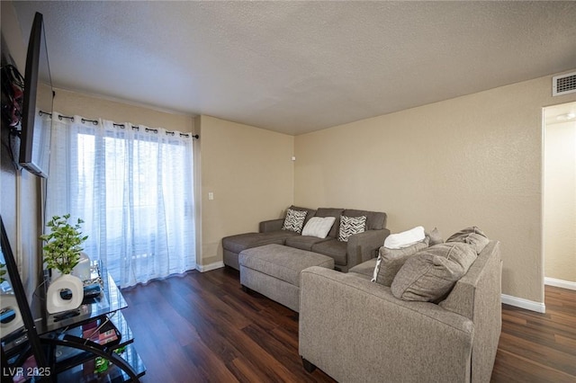 living room featuring a textured ceiling, dark wood-type flooring, and baseboards