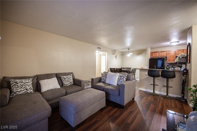 living area featuring baseboards, a textured ceiling, visible vents, and dark wood-type flooring