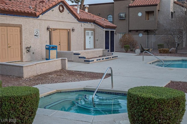 pool with a patio area, fence, and an in ground hot tub