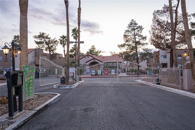 view of road featuring a gate, a gated entry, and curbs