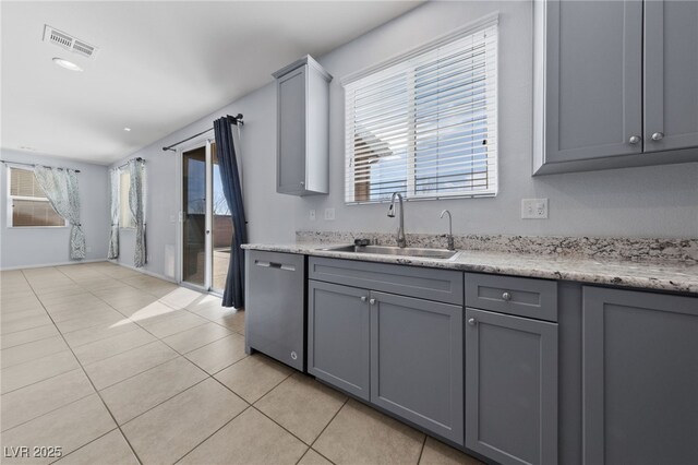 kitchen featuring visible vents, gray cabinetry, a sink, stainless steel dishwasher, and light tile patterned flooring