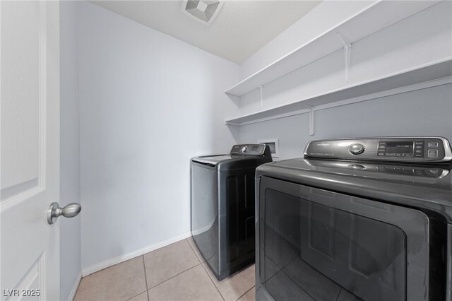 clothes washing area featuring washer and dryer, laundry area, light tile patterned floors, and baseboards