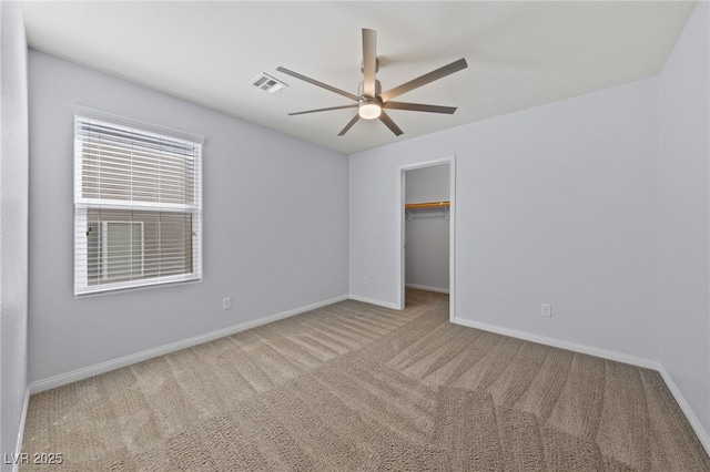 unfurnished bedroom featuring a ceiling fan, baseboards, visible vents, a spacious closet, and carpet flooring