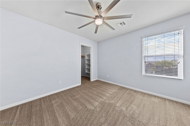 unfurnished bedroom featuring visible vents, a closet, carpet floors, baseboards, and a spacious closet