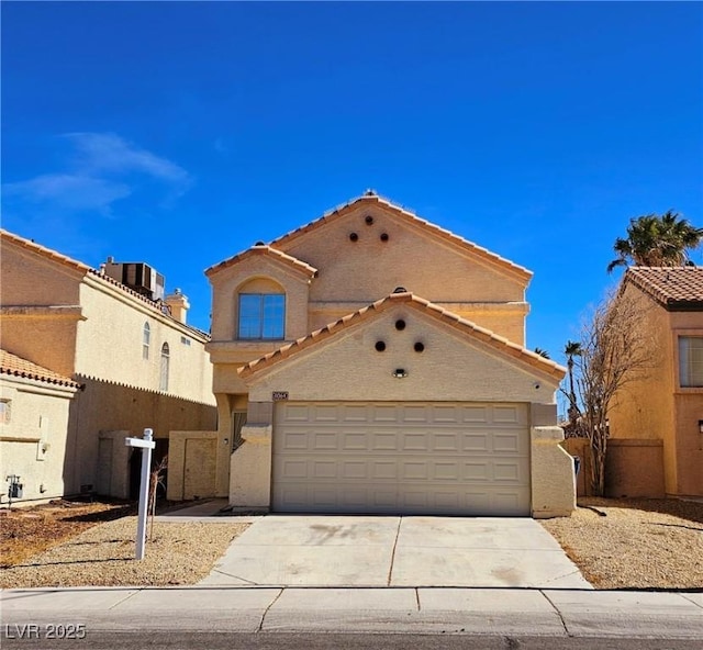 view of front of home with concrete driveway, fence, a tiled roof, and stucco siding